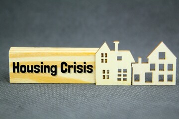 wooden house models and wooden boards with the word housing crisis