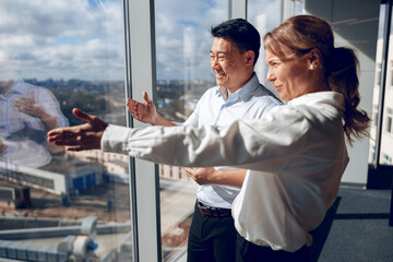 happy confident woman is showing to her asian business partner her project in window. quality photo