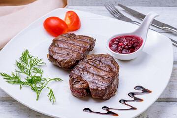 medallions of beef with berry sauce on white wooden table