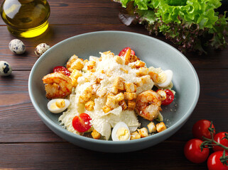 Shrimp tail salad with lettuce, arugula, quail eggs, cherry tomatoes, crackers, olive oil and balsamic vinegar. Top view. Copy space. Close up. Wood background. Lunch, dinner in a cafe, restaurant.