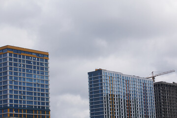 Fototapeta premium Construction of multi-storey buildings. Modern multi-storey building. Completed and under construction buildings. Construction cranes are visible.