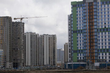 Fototapeta na wymiar Construction of multi-storey buildings. Modern multi-storey building. Completed and under construction buildings. Construction cranes are visible.