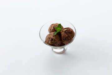 Three scoops of Chocolate ice cream in a glass bowl. On a white background.