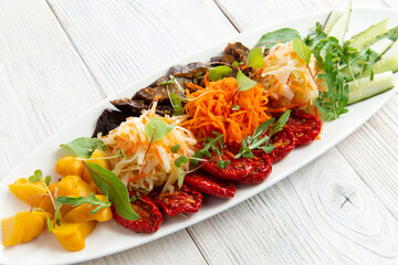 Assorted vegetables in a bowl. Sun-dried tomatoes, pickled squash, cabbage, carrots and cucumbers.