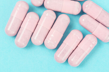 Pink capsule pills on blue background.