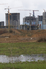 Obraz premium Construction of multi-storey buildings. Modern multi-storey building. Houses with reinforced concrete frame. Work construction cranes.