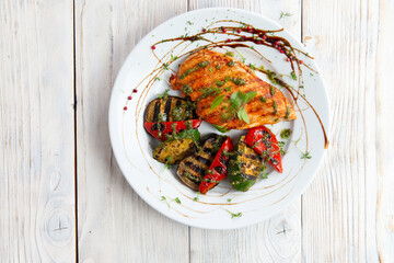 Grilled chicken breast and vegetables. In a plate. View from above.