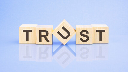 Trust - word is written on wooden cubes on a blue background. close-up of wooden elements
