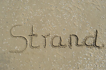 Das Wort Strand in den Sand geschrieben 
