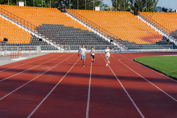 A large group of boys ' children are taught by a coach at the start before running at the stadium...