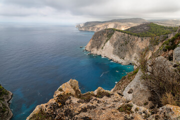 Famous cliff rock, sea, celar blue water, nature in Zakynthos Ionian island, Greece. Amazing view with multicolored clouds, clear sky. Island of lovers. Doors to heaven.