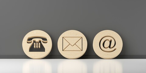 Wooden round telephone, envelope letter and e-mail symbols leaning against dark grey wall background, contact us symbols or banner