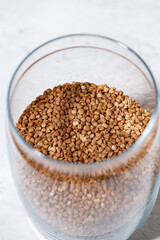 buckwheat groats in a glass jar on white background, vertical