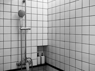 Chrome shower set on black and white grid tiles wall, the interior of modern shower room space box in the bathroom corner with copy space.