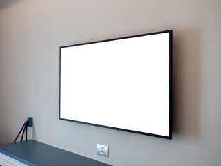 Side view of mockup white blank space on TV screen on the wall near the plug and empty shelf in the hotel bedroom.