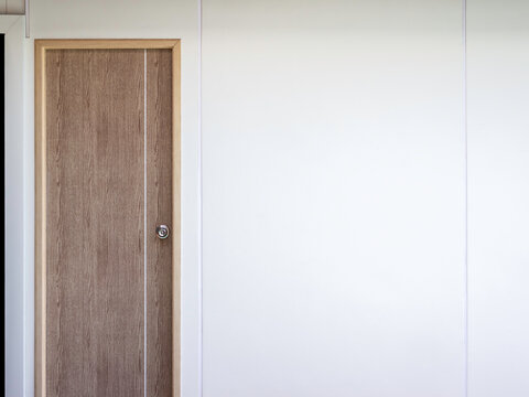 Empty White Plain Cement Wall Building Background Near The Closed Wooden Door With Copy Space. Blank Space Mockup For Picture Frame, Artwork Decoration.