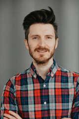Obraz premium Portraot of Handsome young bearded man in a plaid shirt by a grey background