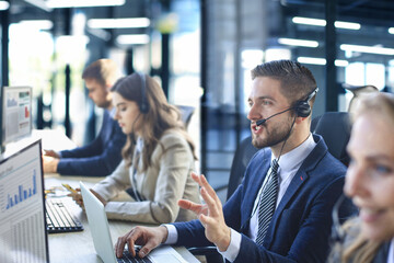 Portrait of call center worker accompanied by his team. Smiling customer support operator at work.