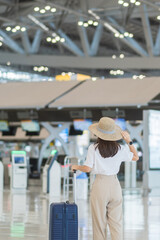 Young woman hand holding luggage handle before checking flight time in airport, Transport,...