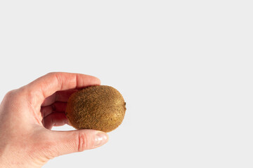 Hand holding ripe unpeeled kiwi fruit on white background, copy space. Kiwi is a natural dietary...