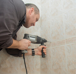the builder in the bathroom using a hammer drill holes to install shelves