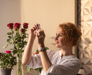 a girl with red curly hair is engaged in handmade production of exclusive bracelets from different stones