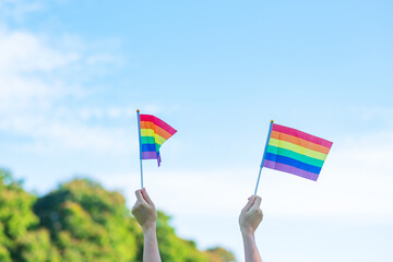 hands showing LGBTQ Rainbow flag on nature background. Support Lesbian, Gay, Bisexual, Transgender and Queer community and Pride month concept