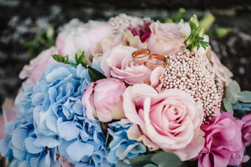 Wedding rings bride and groom on the background bridal bouquet with flowers roses and greenery.