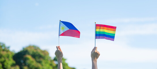 hands showing LGBTQ Rainbow and Philippines flag on nature background. Support Lesbian, Gay, Bisexual, Transgender and Queer community and Pride month concept