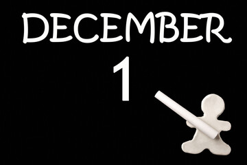 A small white plasticine man writing the date 1 December on a black board. Business concept. Education concept.
