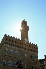 Fototapeta premium OLD PALACE called Palazzo Vecchio with the high tower called Torre di Arnolfo di Cambio in Florence in Italy and the sun coming out from behind