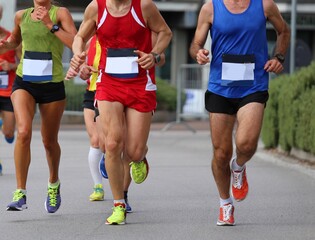 athletic runners during the foot race in the city on the asphalt road and sportswear and running shoes