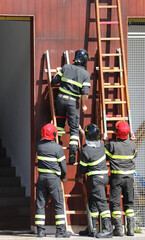 four firefighters in action in the firehouse with the long ladder simulating a rescue