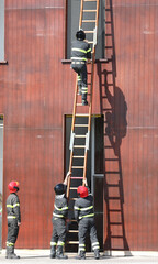 firefighters in action during the exercise in the fire station with the long ladder and the foreman...