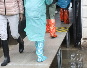 pedestrians over the elevated walkway during a terrible flood in the island of Venice in Italy
