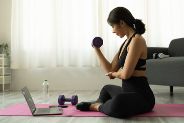 Fototapeta na wymiar Young asian woman doing fitness exercises at home through virtual class