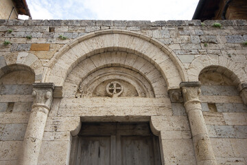 Fototapeta na wymiar Medieval vaulted arch with cross above the door jamb in the historic village of Monteriggioni