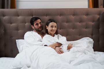 Fototapeta premium Man hugging his wife in bed of hotel room