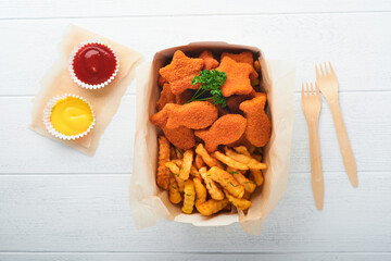 Fish and Chips british fast food. Fish Sticks with french fries set on takeaway paper plate on white wooden background. Traditional British authentic street food or takeaway food. Mock up.