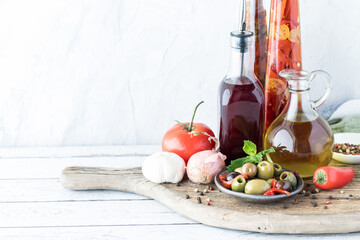 Oil and red wine vinegar in glass bottles with olives and peppercorns.
