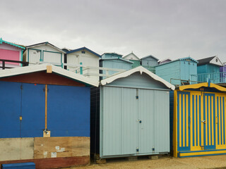 Naklejka premium Tiers of colourful timber beach huts, ready for holiday makers, forming regular, geometric, near-abstract patterns on the seashore of Frinton-on-Sea.