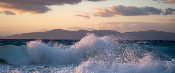 Sea ​​wave at sunnsethitting a rock on the beach.