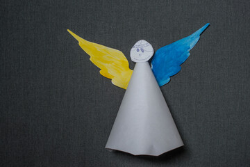 An angel with yellow and blue wings is on a gray background.