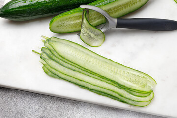 Cucumber sliced on marble board with knife. Food preparing