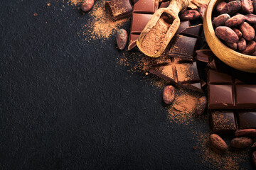 Chocolate . Composition of cocoa powder, grated and bean cocoa bars and pieces of different milk and dark chocolate on black background. Baking Chocolate Texture. Top view with copy space. Mock up.