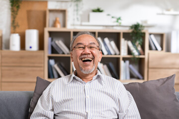 Healthy Asian Elderly man with white hairs smile and laughing so happiness and cheerful at home.Portrait of senior man sit on couch smile enjoying retirement at home .Happiness Elderly Concept