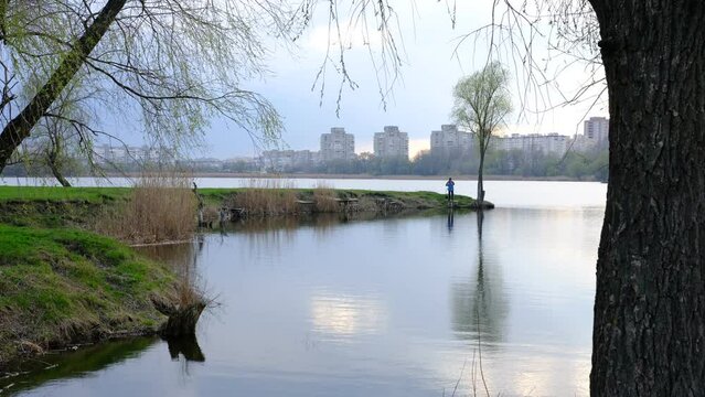 Fisherman in sunset on the city lake cheha in Sumy, Ukraine. Beautiful reflect from sky and clouds in water