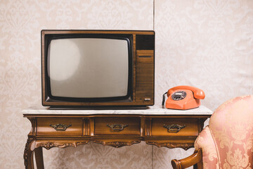 Old tv and telephone in an interior place with decoration in retro style.