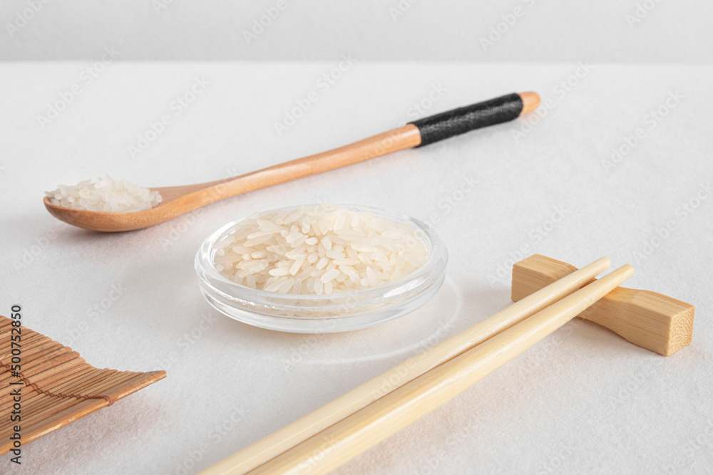 Wall mural White rice in a glass bowl with chopsticks and a spoon of rice