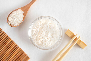White rice in a glass bowl with chopsticks and a spoon of rice